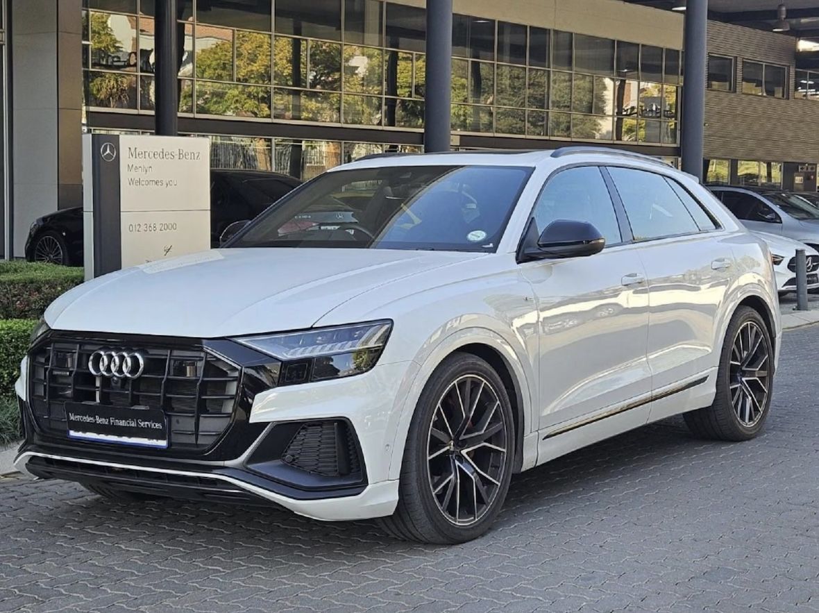 Before enhancement - white Audi SUV at Mercedes-Benz dealership with busy background and dealership signage